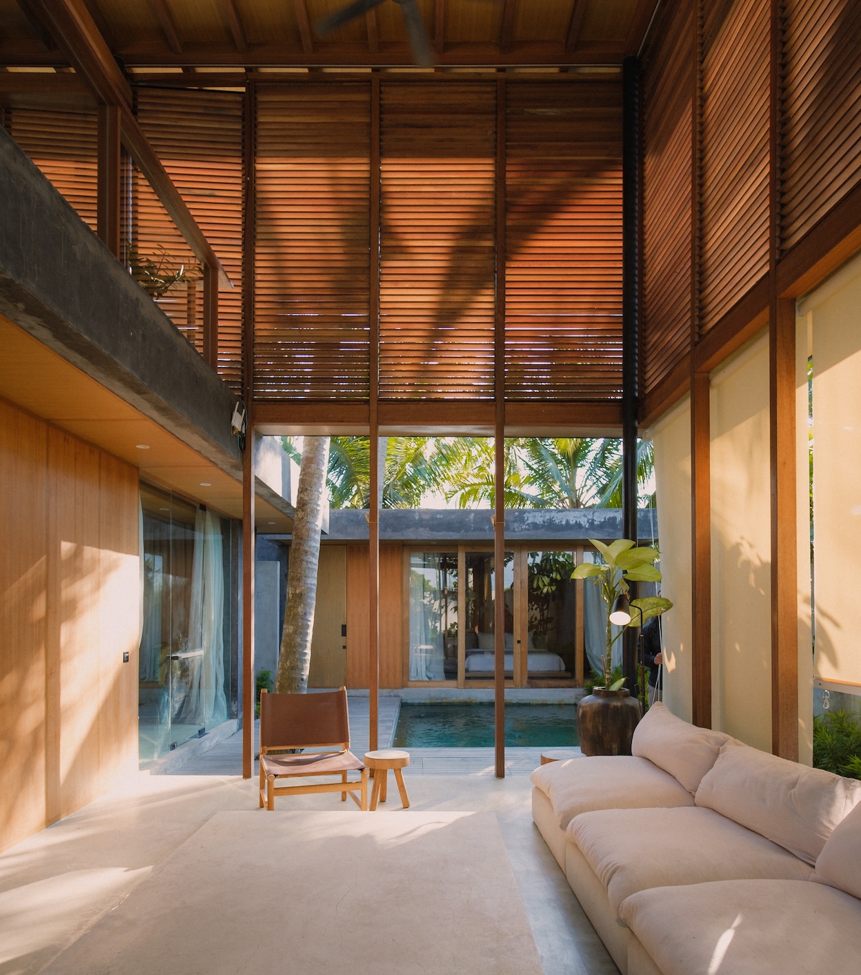 1st villa living room at rumah amadangi showing double height ceilings, plunge pool, and wooden screens surrounding the upper portion of the space