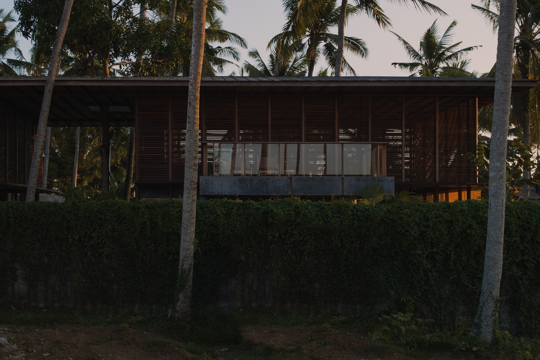 Rear view of rumah amadangi showing upper wooden elements, extruding terrace, and surrounding trees