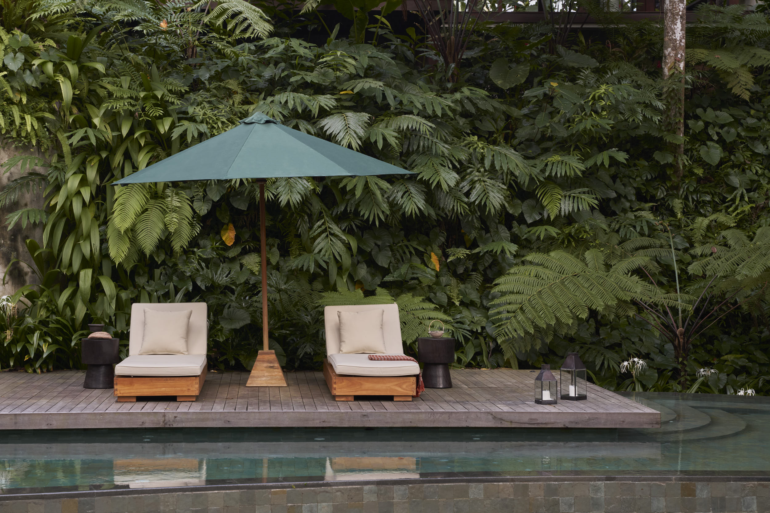 Lansdscape view of the swimming pool showing sun loungers and umbrella