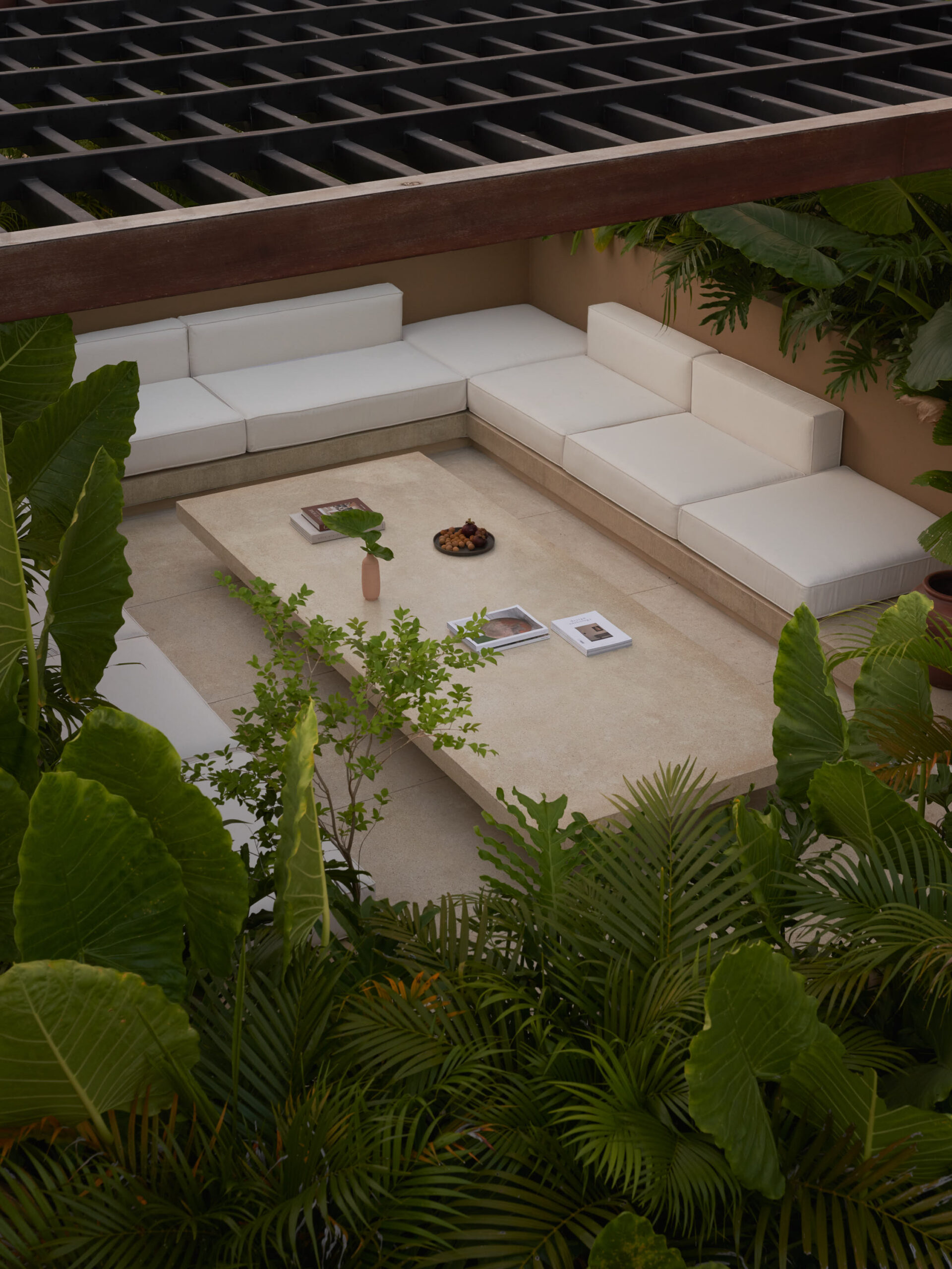 View of the roof top living space showing the sofa, a terrazzo coffee table, and plants surrounding the space