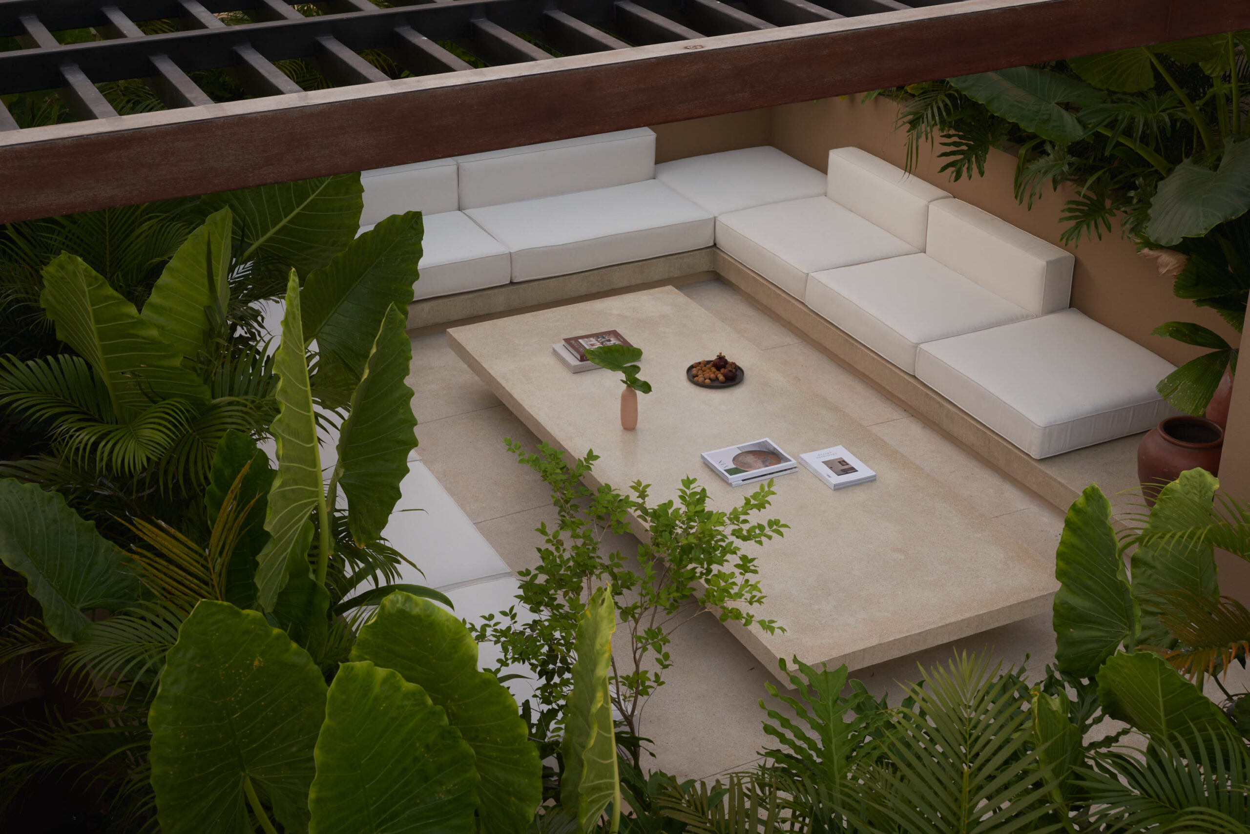 Horizontal view of the roof top living space showing the sofa, a terrazzo coffee table, and plants surrounding the space