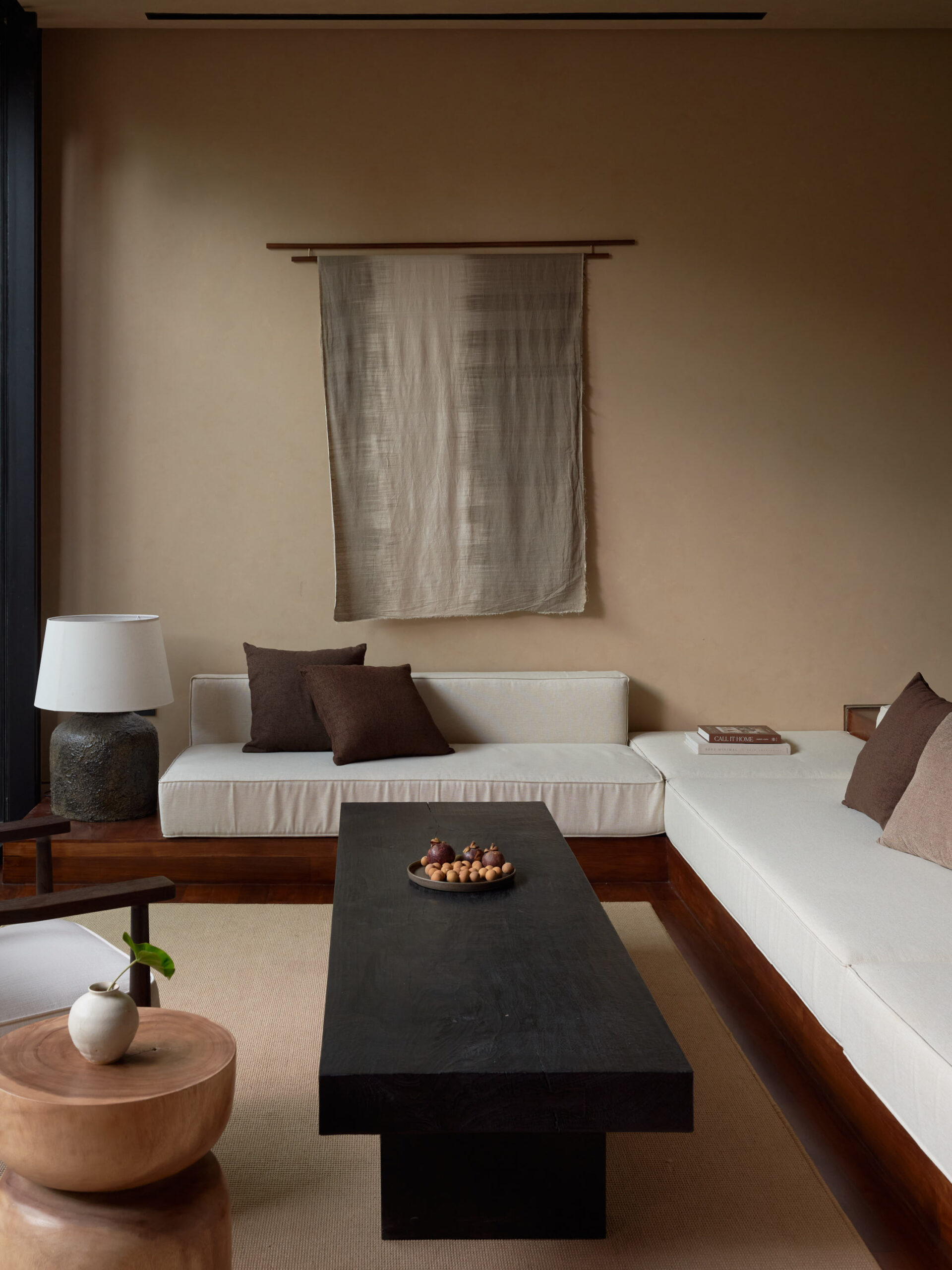 Living room at leaf berawa showing the sunken sofa, solid teak wood coffee table and natural dye cloth art work