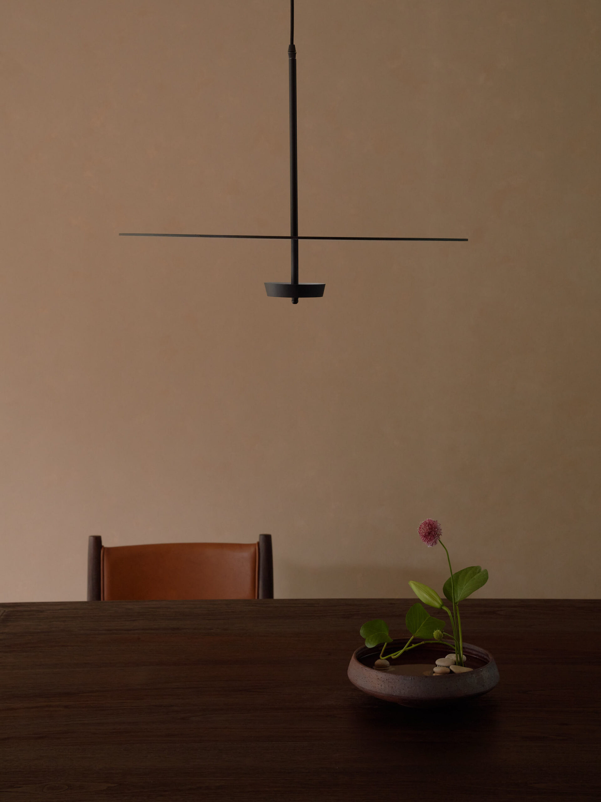 Detailed photo of the dining table, pendant lamp, flower arrangement, and leather dining chair