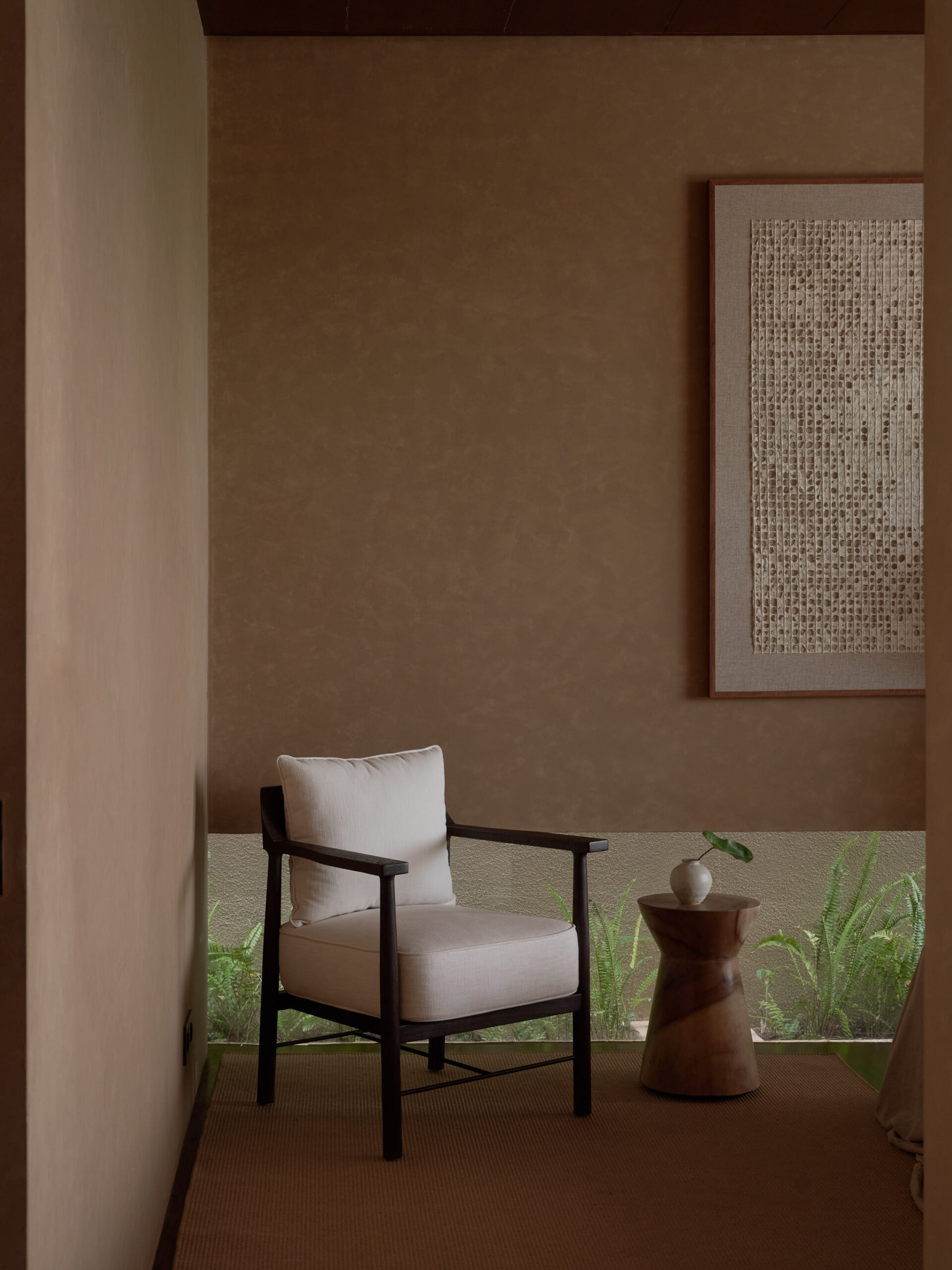 Master Bedroom corner seating area with arm chair and side table and banana paper art work