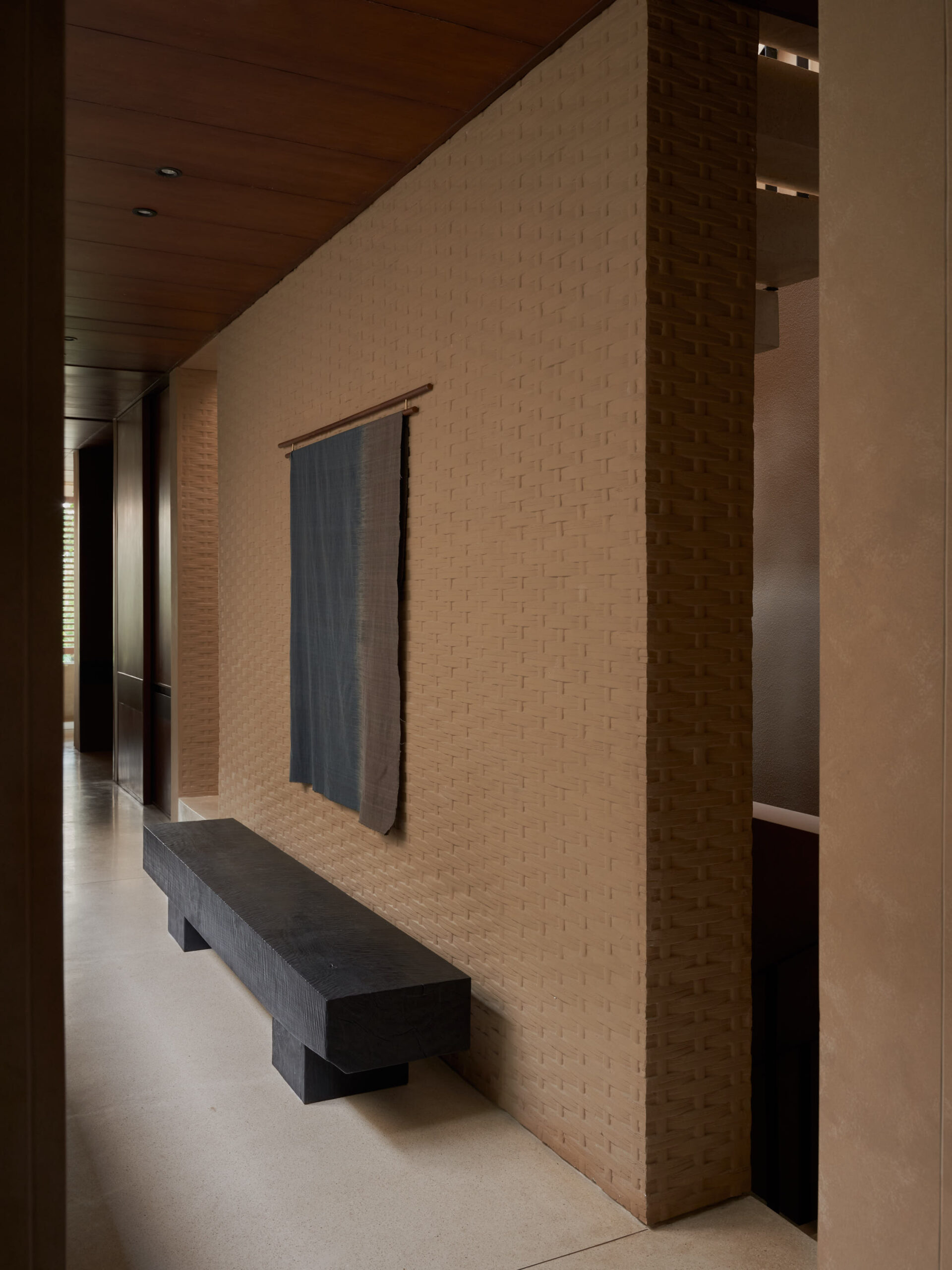 2nd floor foyer showing a solid teak wood bench, natural dye cloth artwork and the bamboo presses concrete wall