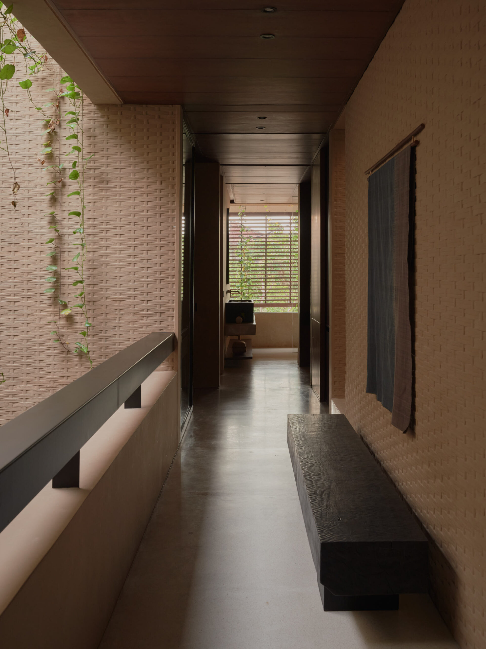 2nd floor corridor connecting the bedrooms showing the master bathroom vanity counter and seeing through to the wooden screens of the building facade and the featured bamboo pressed concrete walls
